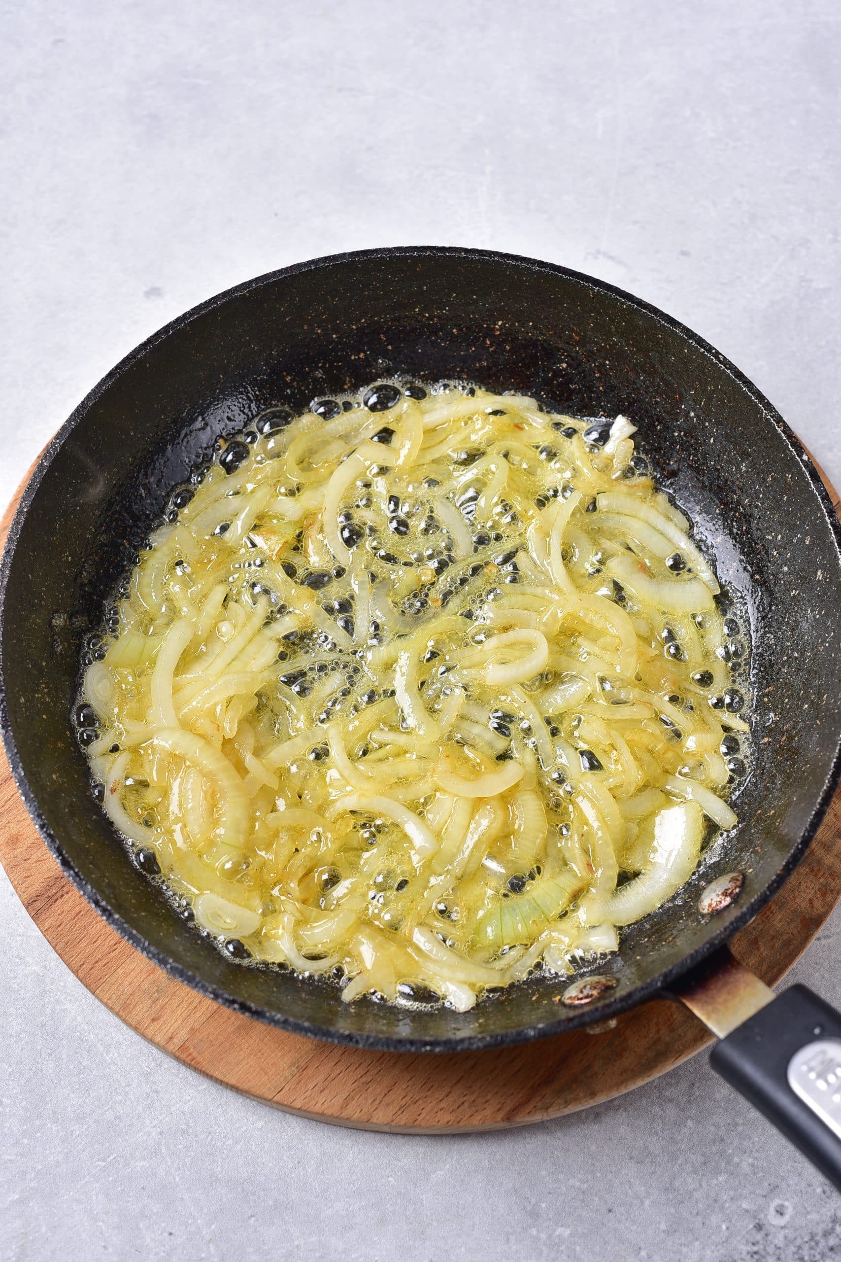 thinly sliced yellow onions caramelizing in butter in a black skillet