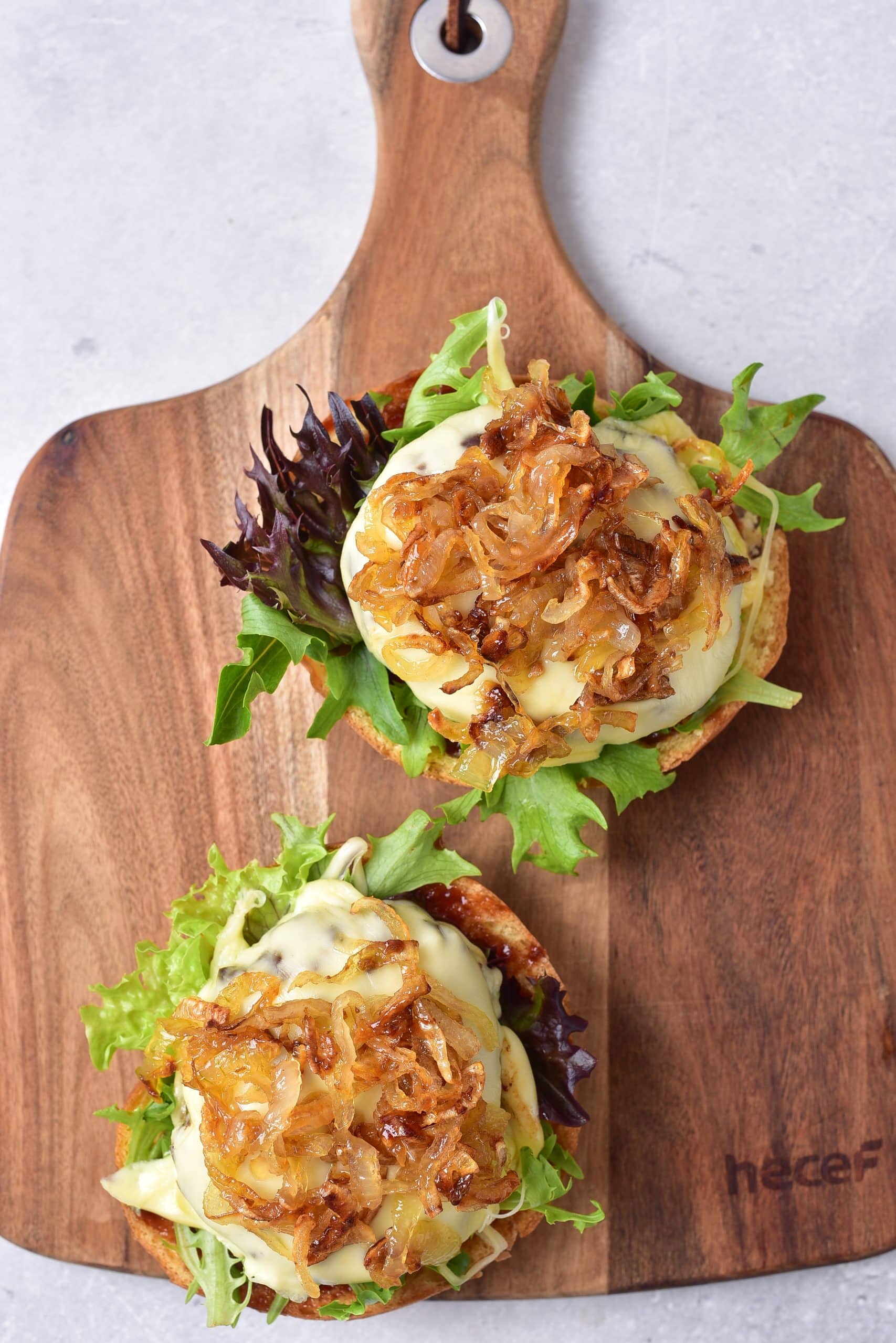 air fryer burgers topped with caramelized onions on a bed of lettuce on a bun