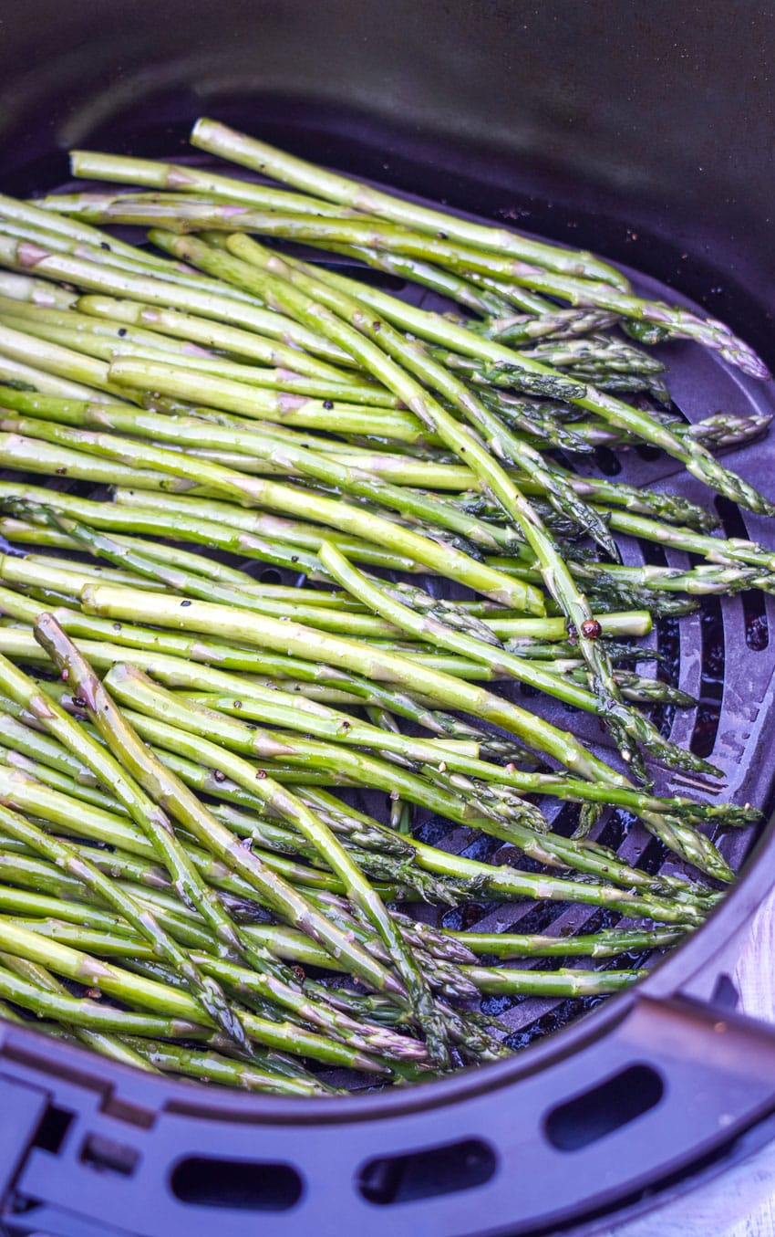 stalks of roasted asparagus in the basket of an air fryer
