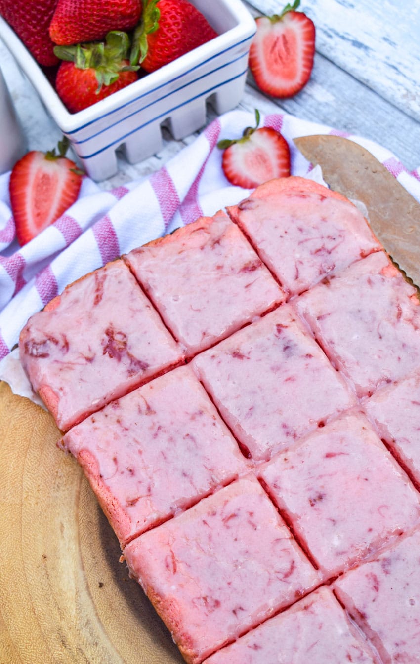 sliced strawberry brownie squares on a wooden cutting board