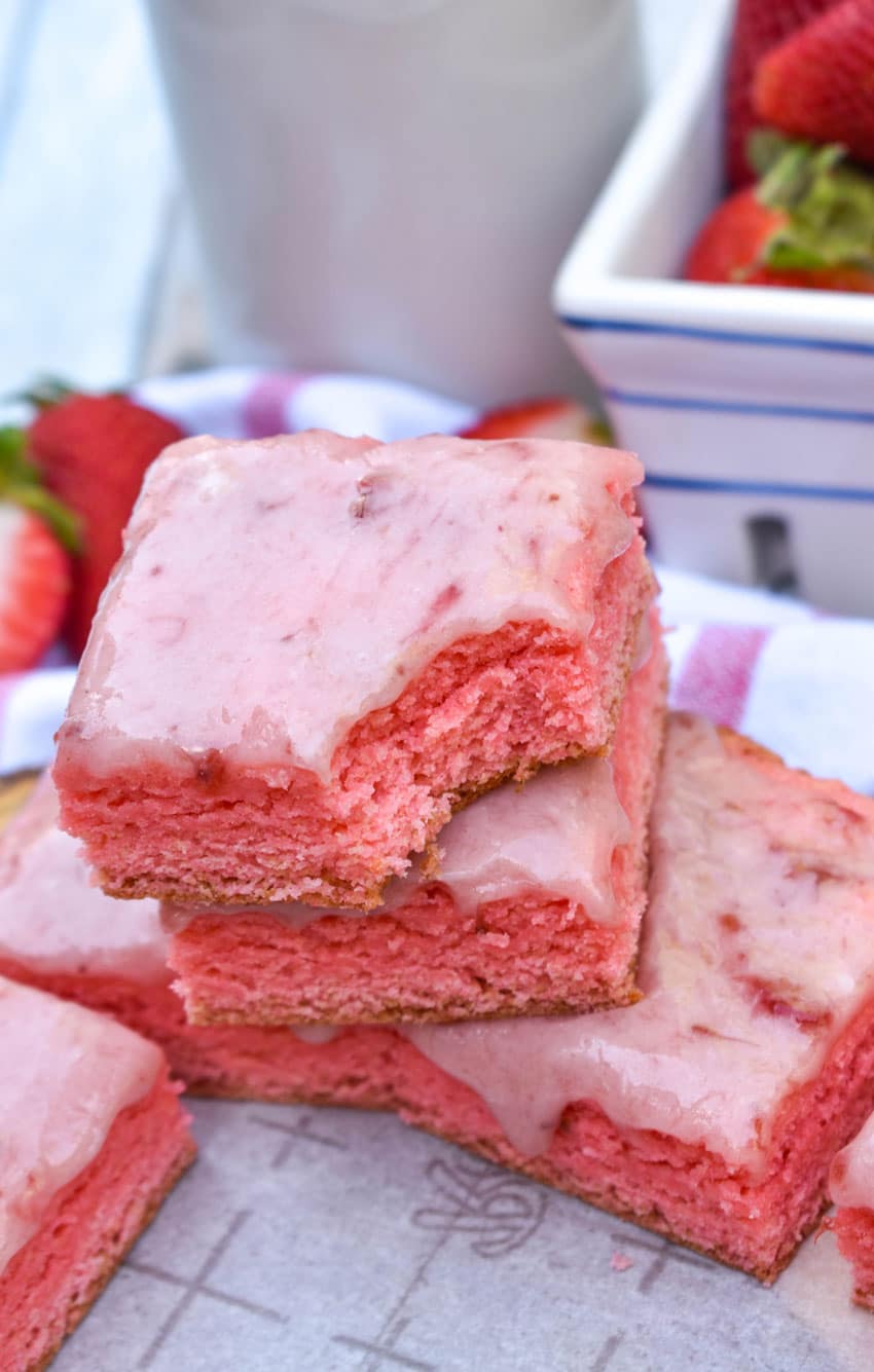 strawberry brownies stacked on a sheet of white parchment paper