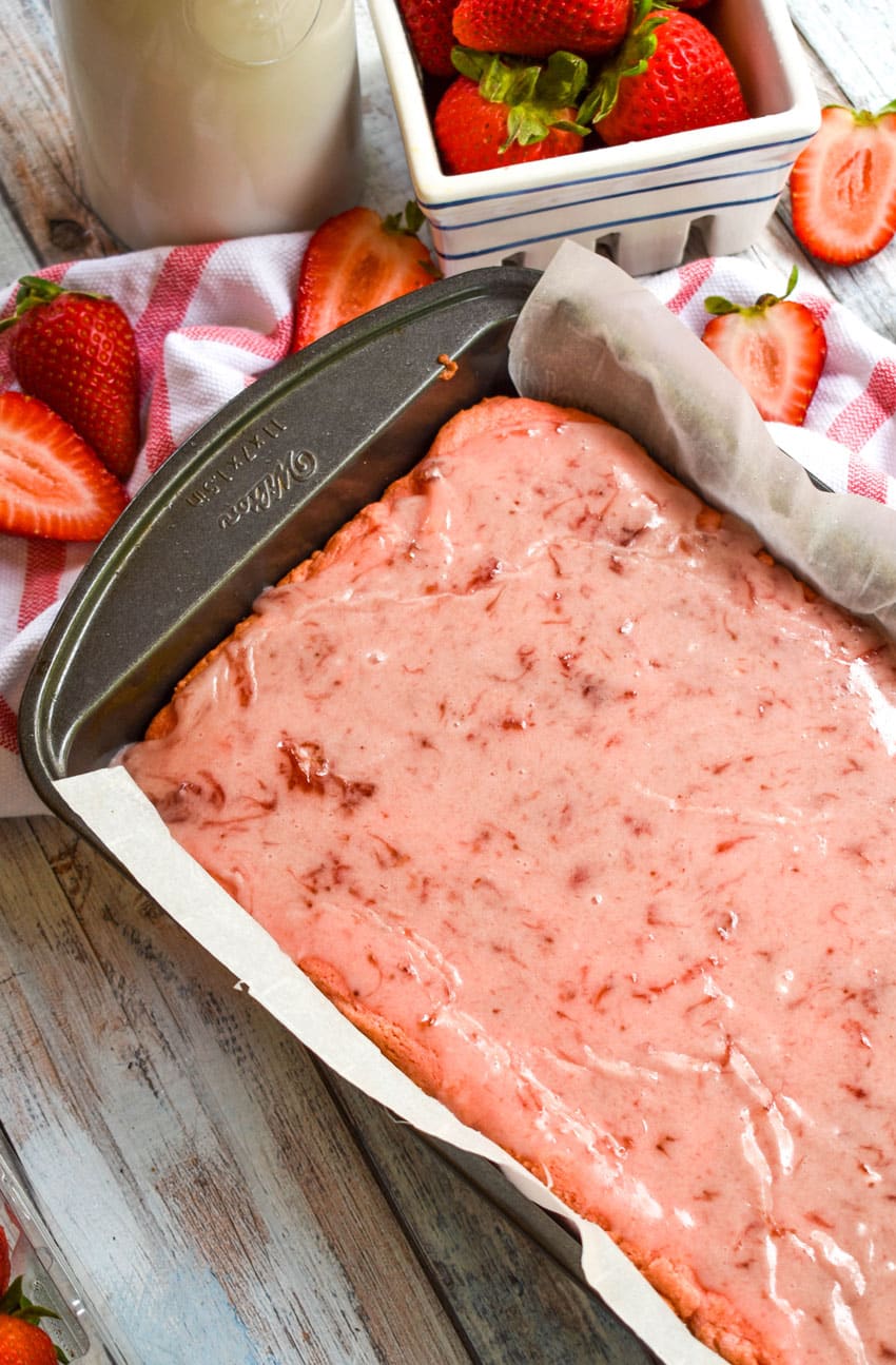 strawberry brownies with strawberry glaze in a metal baking pan