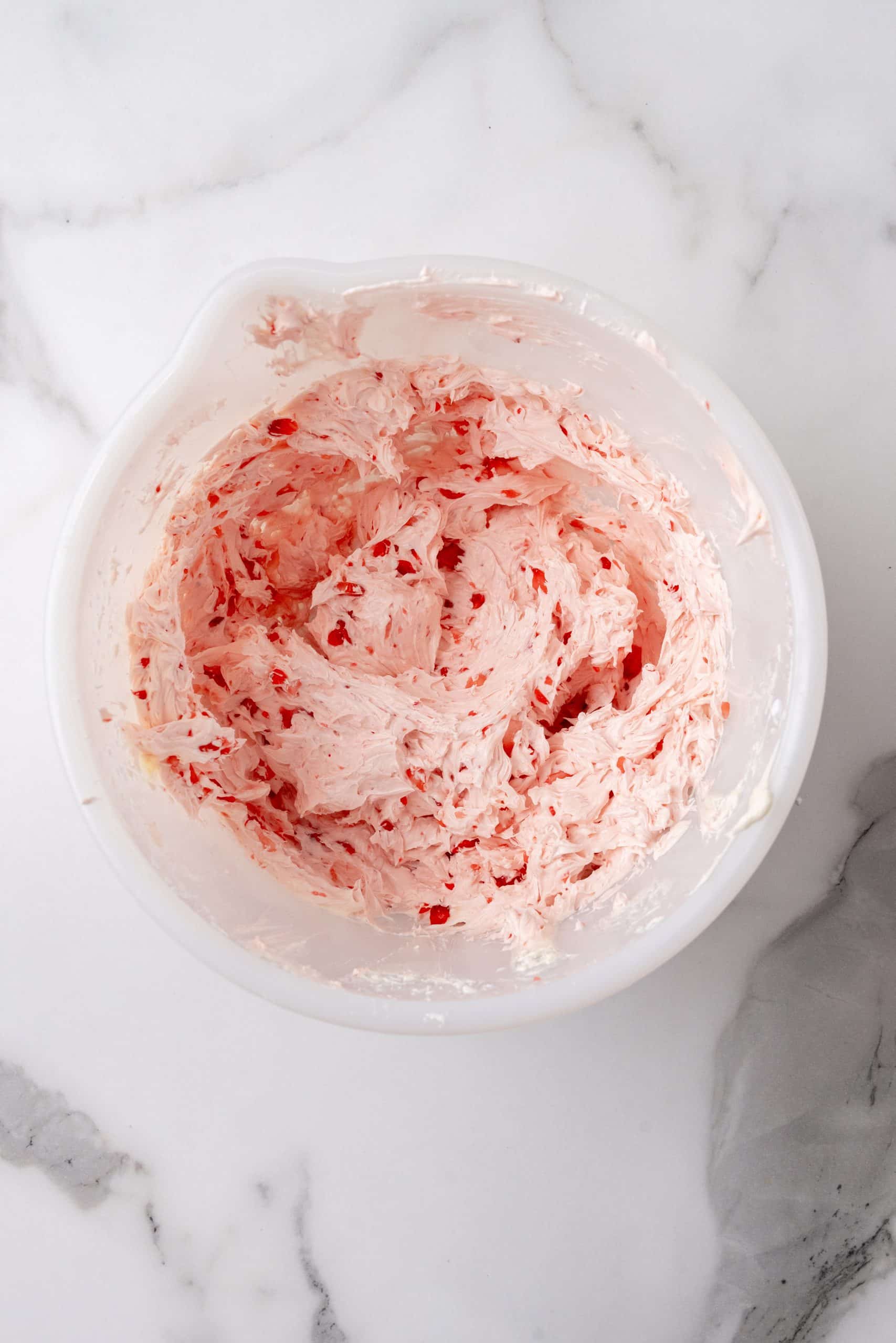 homemade strawberry butter in a large white mixing bowl on a marbled counter top