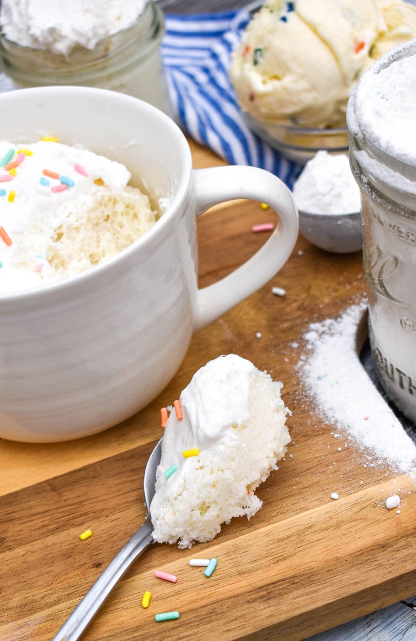 a small spoon with a piece of microwave mug cupcakes on  it resting on a wooden cutting board