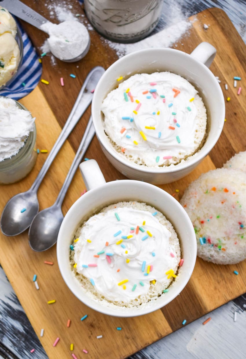 two microwave mug cupcakes on a wooden cutting board