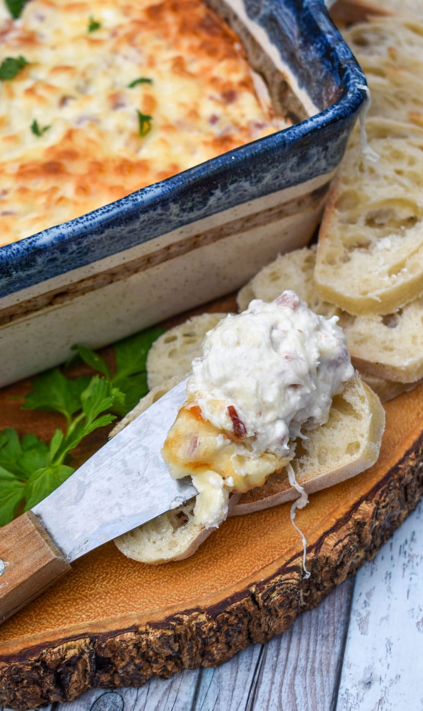 chicken cordon bleu dip on a cheese spreader resting on slices of baguette bread