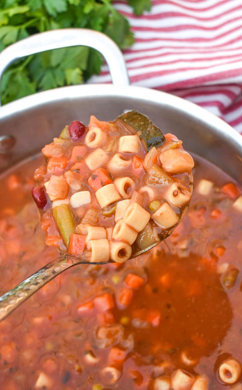a silver ladle holding up a scoop of italian minestrone soup