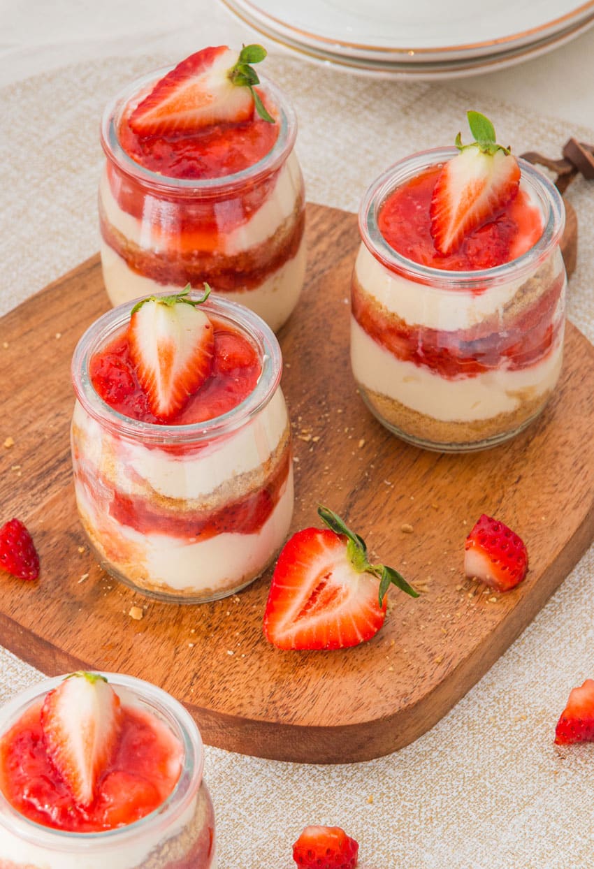 strawberry cheesecake cups on a wooden cutting board