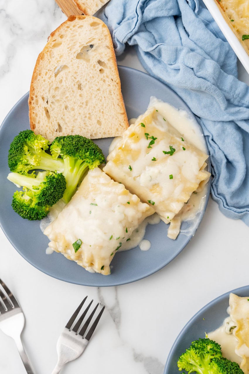 white chicken lasagna roll ups and steamed broccoli on a small blue plate