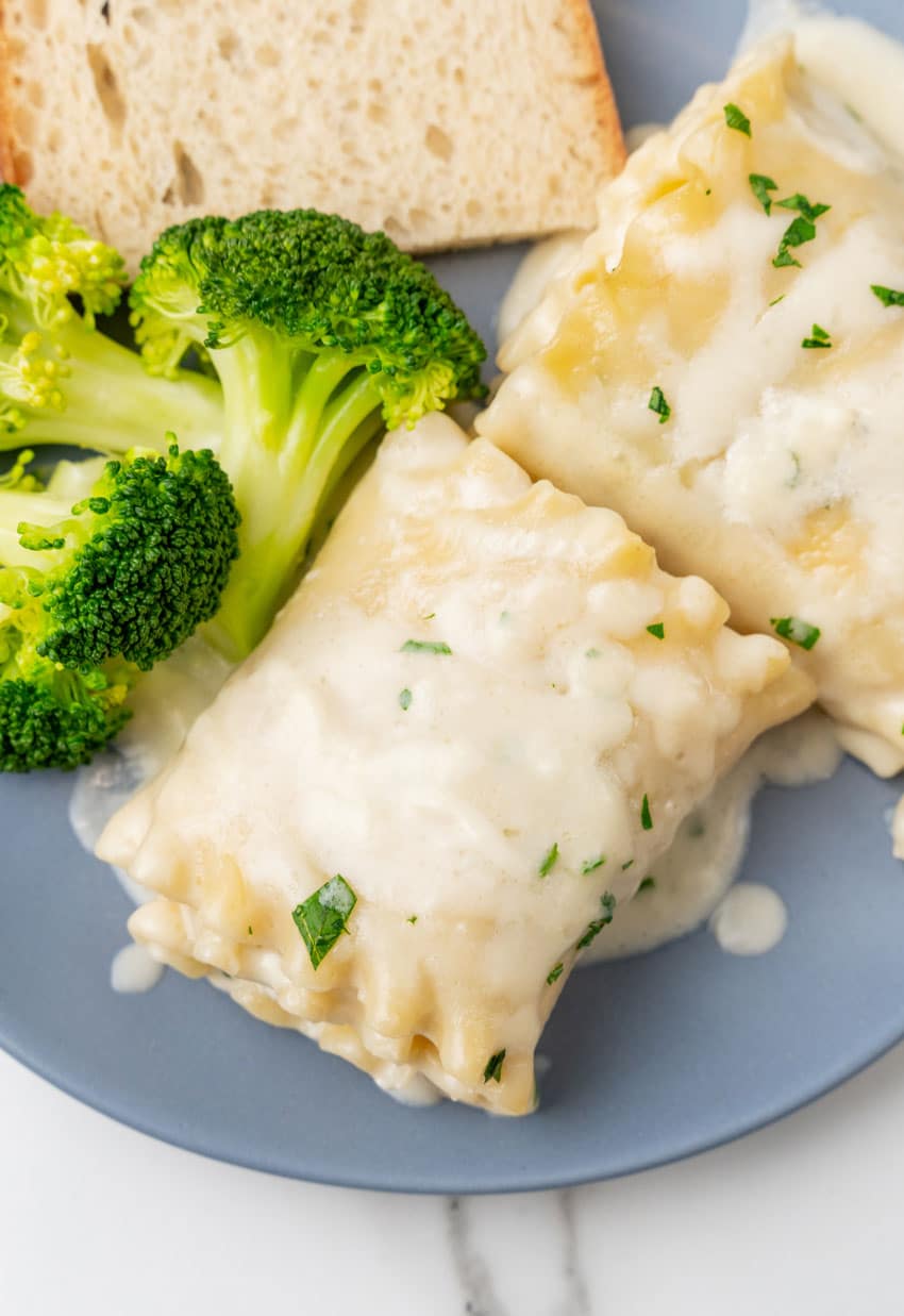 white chicken lasagna roll ups and steamed broccoli on a small blue plate