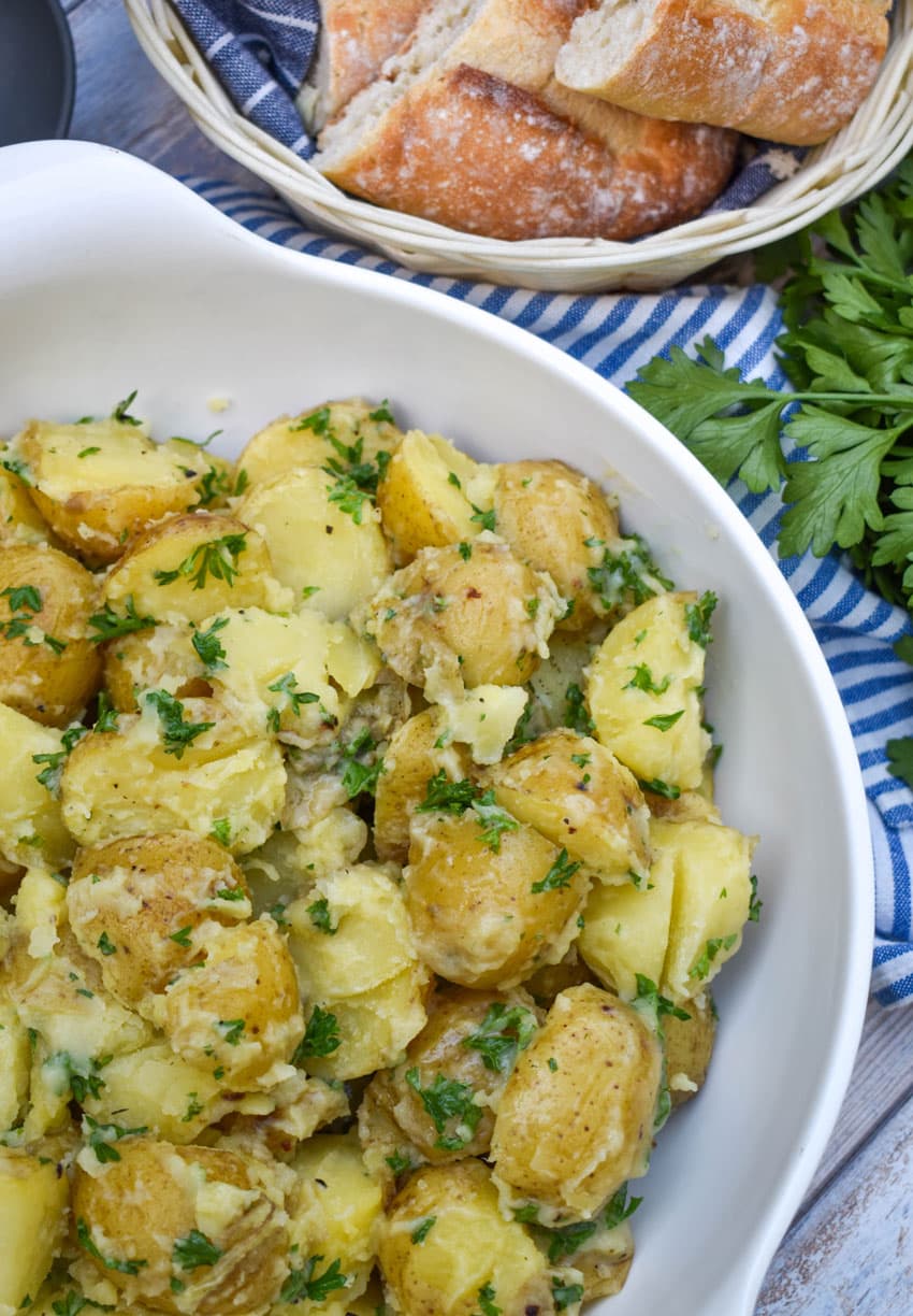 butter and parsley potatoes in a white serving bowl