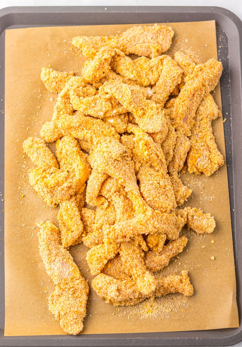 breaded chicken strips laying on a piece of brown parchment paper