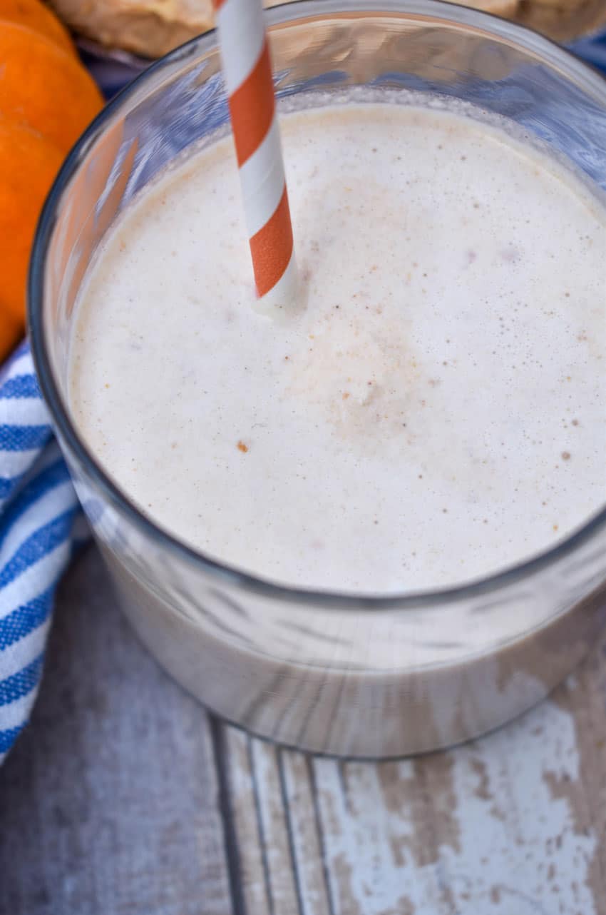 a close up of a pumpkin pie milkshake in a small glass jar