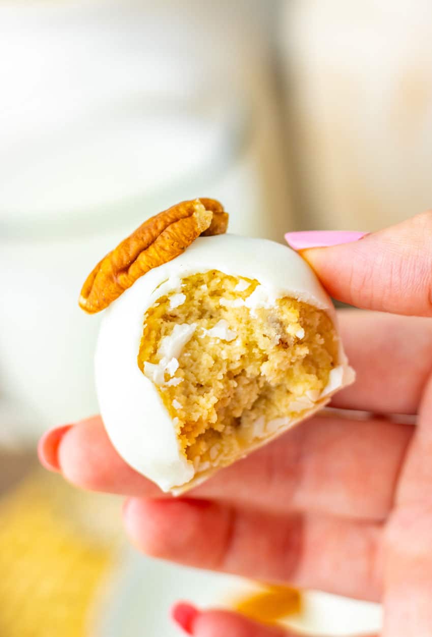 a hand holding up a bitten pecan pie truffle showing the inside filling