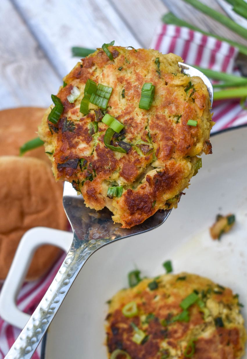 a silver spatula holding up a pan fried tuna patty