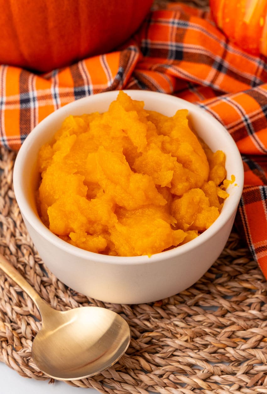 an overhead image showing homemade pumpkin puree in a small white bowl