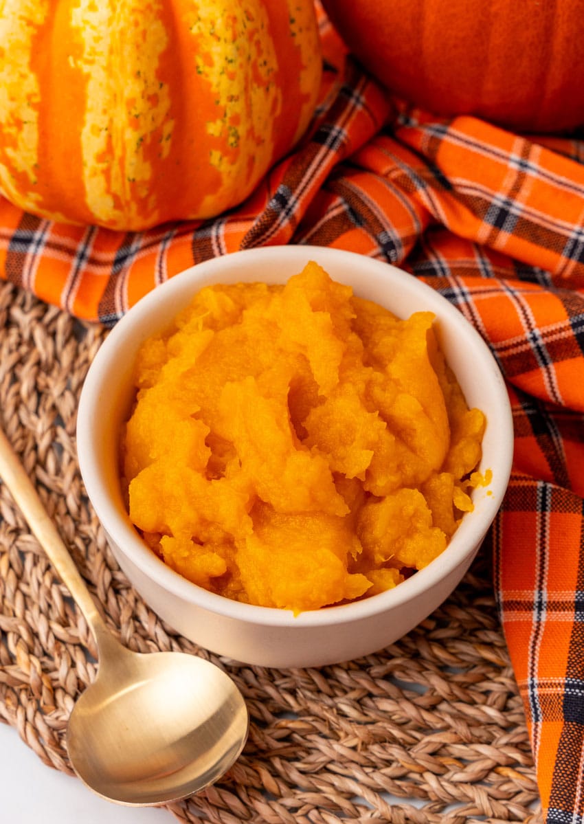 an overhead image showing homemade pumpkin puree in a small white bowl