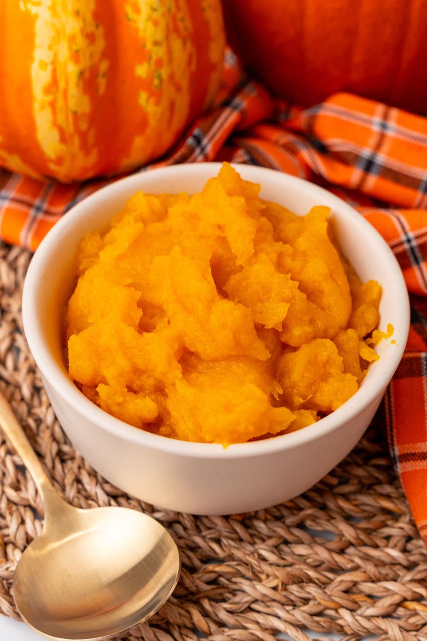 an overhead image showing homemade pumpkin puree in a small white bowl