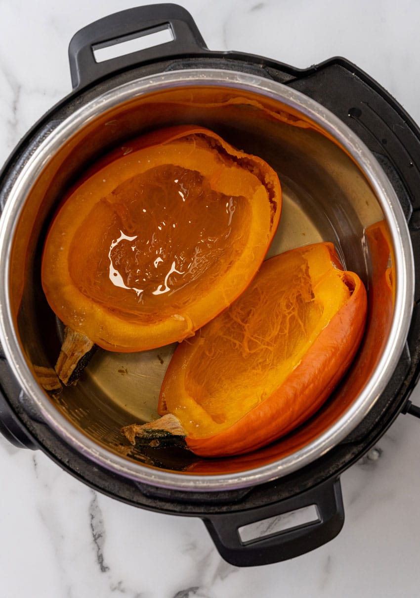 two cooked halves of a pie pumpkin in the bowl of an instant pot