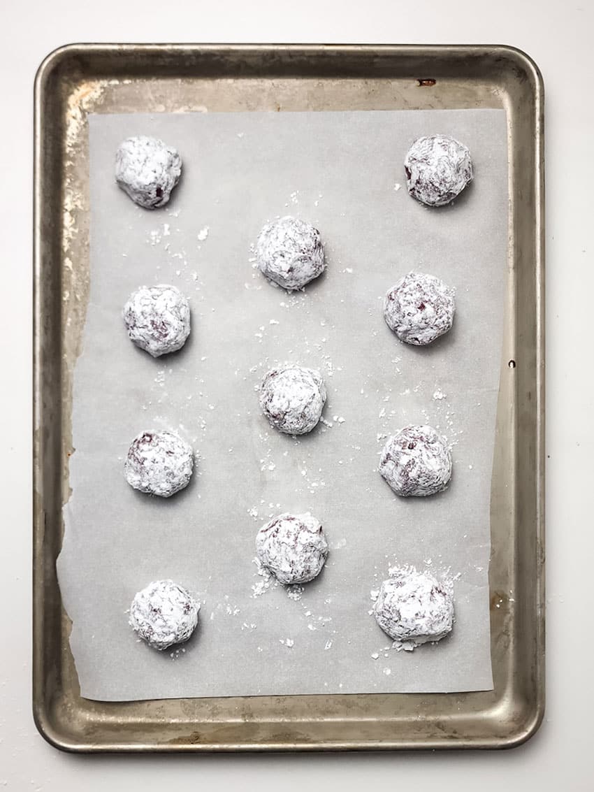 red velvet crinkle cookies arranged in rows on a parchment paper lined baking sheet