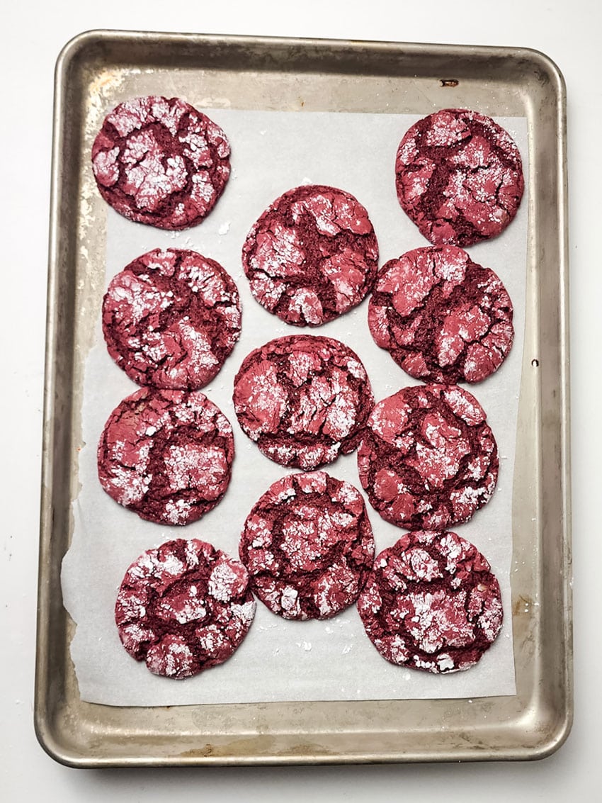 red velvet crinkle cookies arranged in rows on a parchment paper lined baking sheet