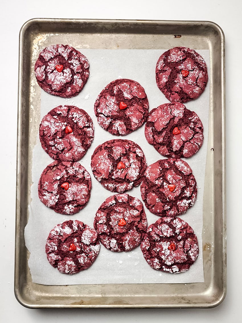 red velvet crinkle cookies arranged in rows on a parchment paper lined baking sheet