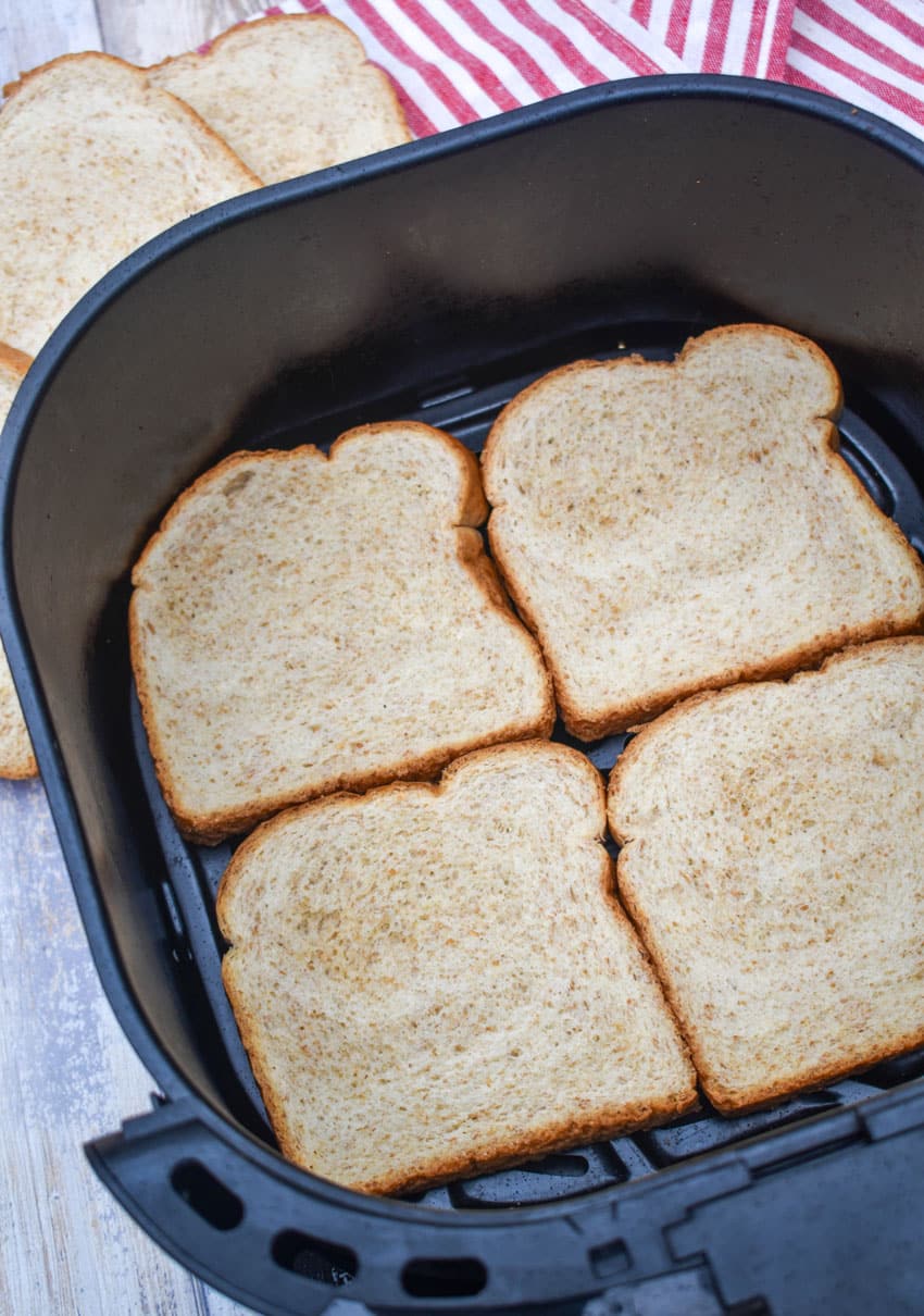 four pieces of sandwich bread in the basket of an air fryer