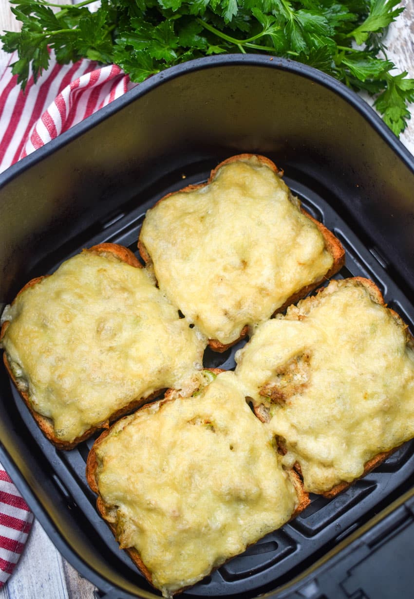 open face tuna melt sandwiches in the basket of an air fryer