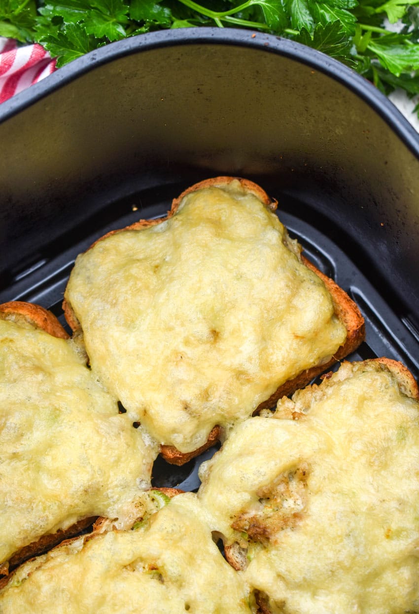 open face tuna melt sandwiches in the basket of an air fryer