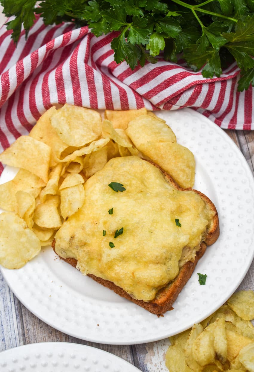 an air fried tuna melt sandwich with potato chips on a small white plate