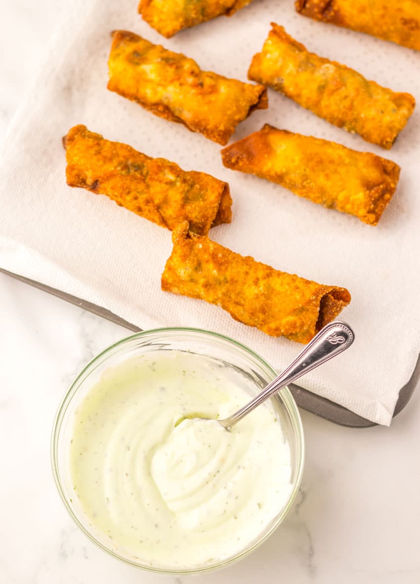 fried egg rolls in two rows on a paper towel lined baking sheet
