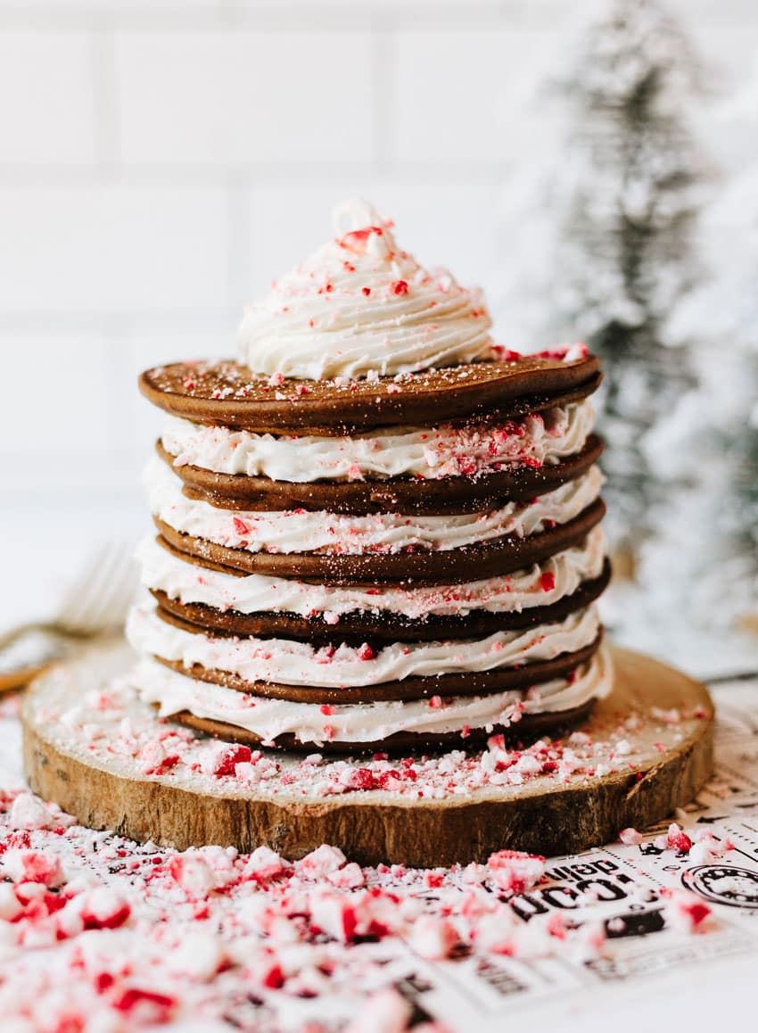 a stack of peppermint pancakes on a wooden cutting board surrounded by peppermint candy pieces
