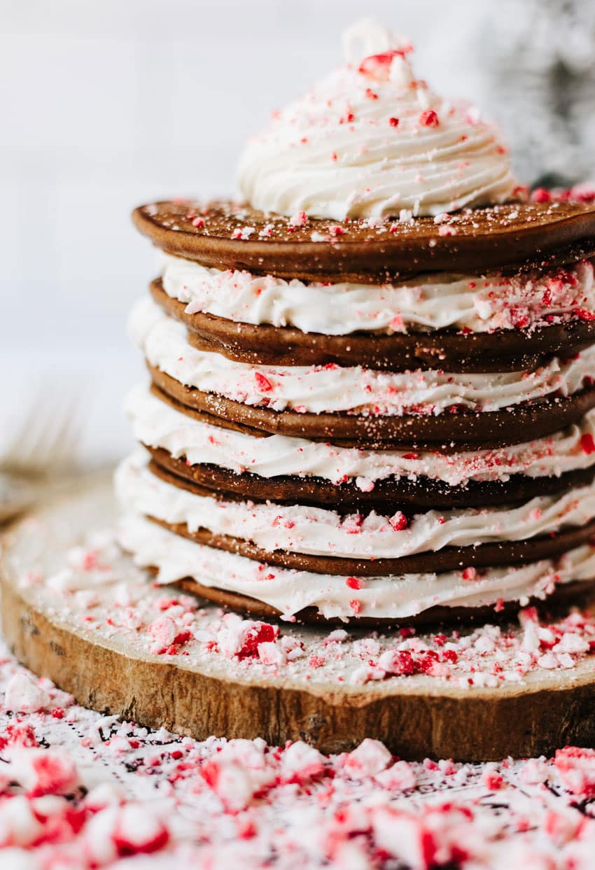 a stack of peppermint pancakes on a wooden cutting board surrounded by peppermint candy pieces