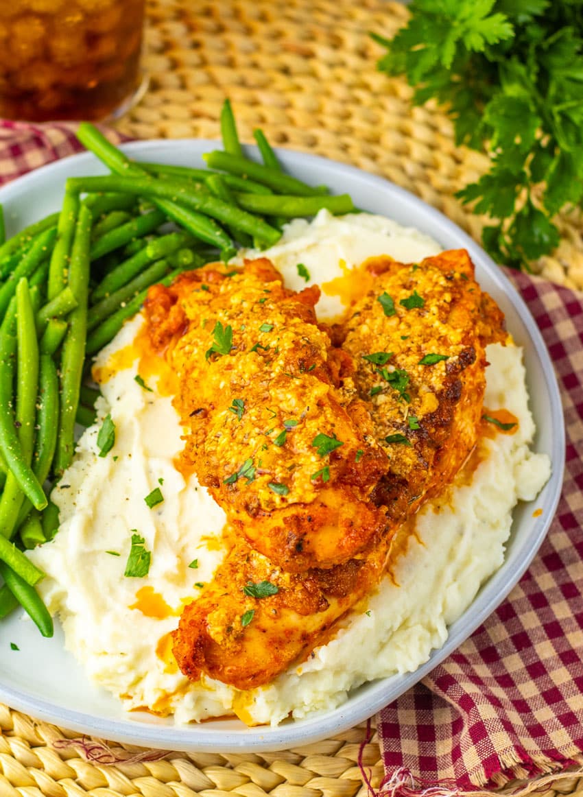 garlic parmesan baked chicken over mashed potatoes on a gray plate