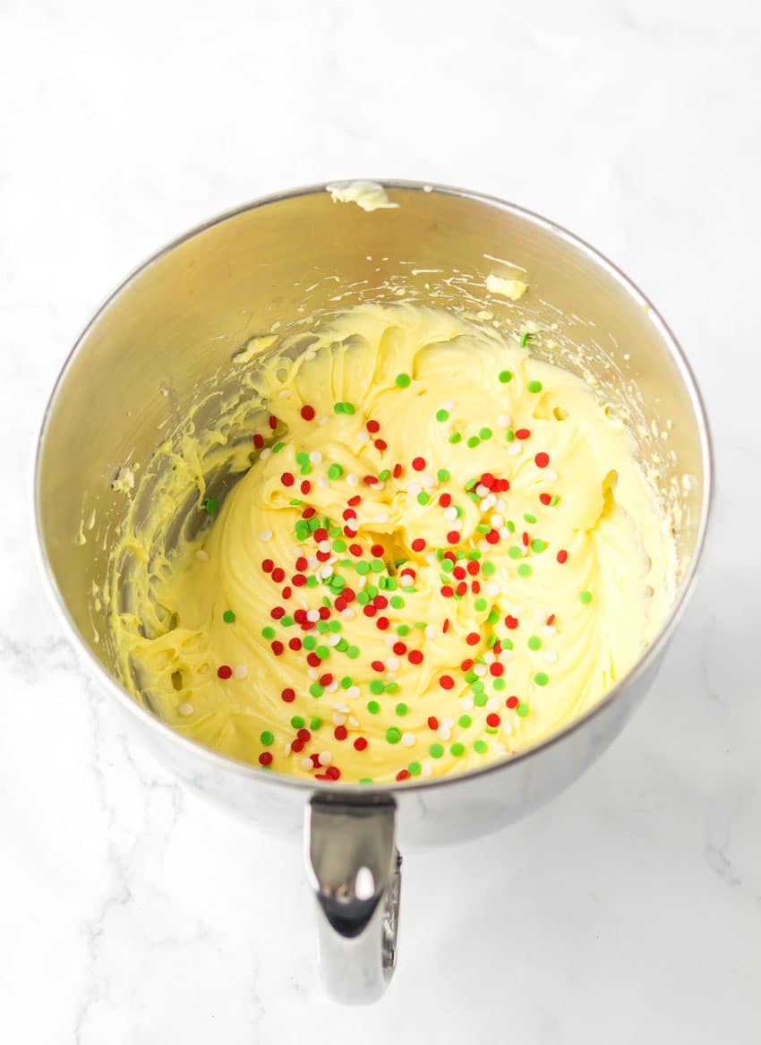 sprinkles resting on vanilla pudding in a metal mixing bowl