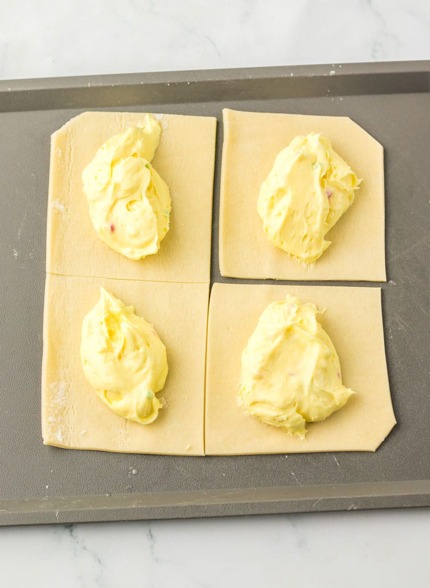 dollops of vanilla pudding on cut pie crust squares on a metal baking sheet