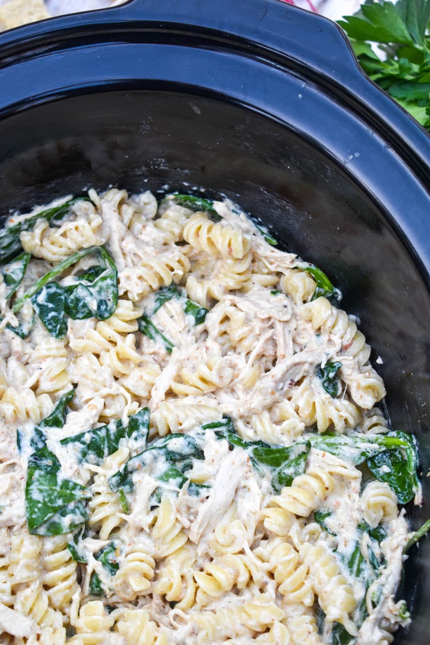 chicken caesar pasta in the black bowl of a slow cooker