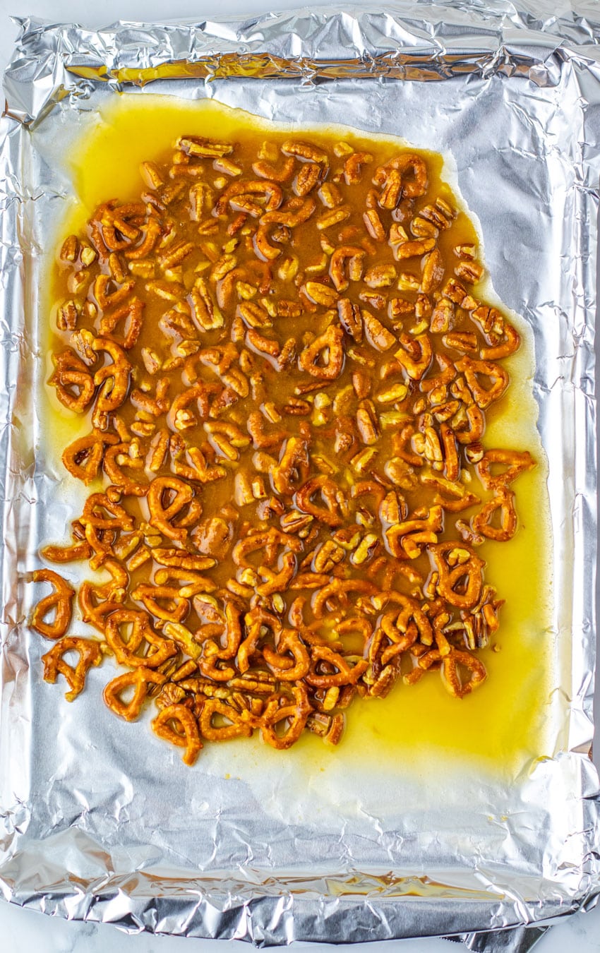 caramel coated pretzel pieces spread out on a foil lined baking sheet