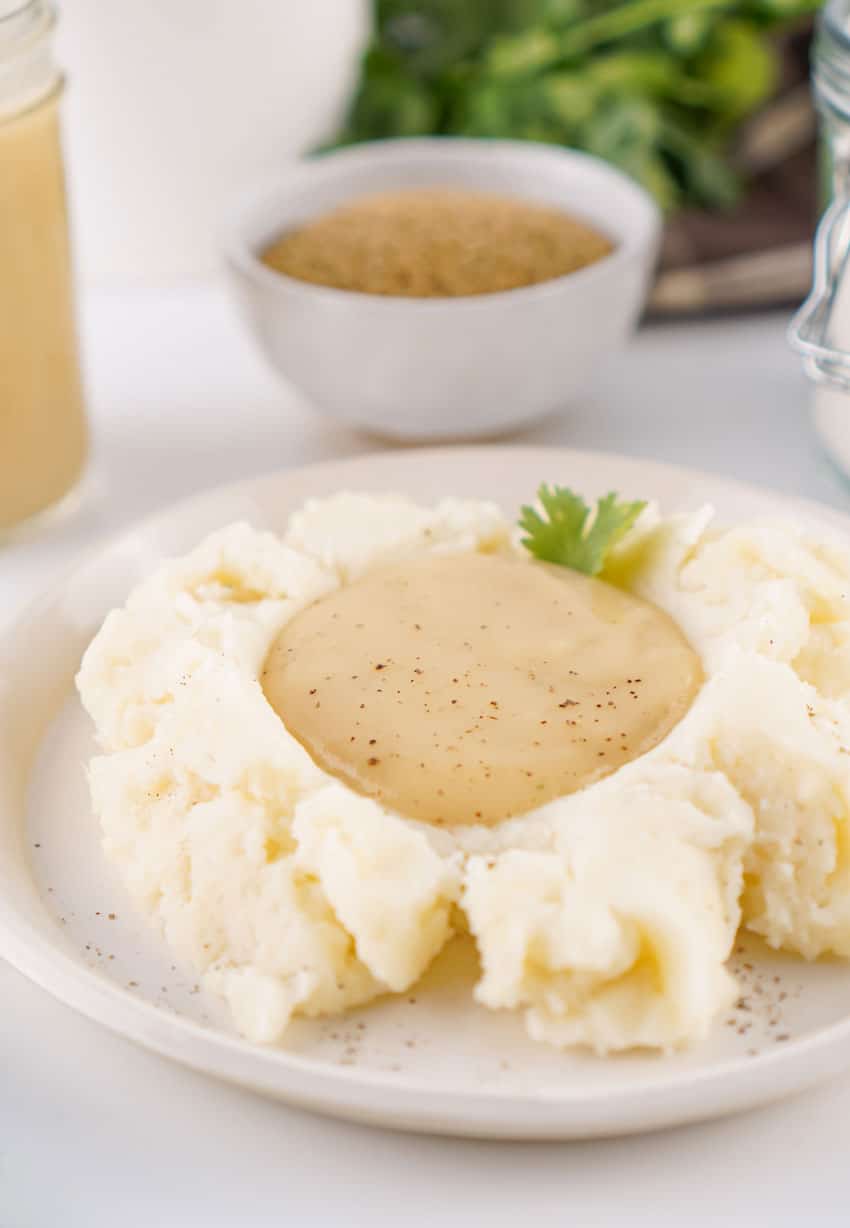 homemade brown gravy mix gravy over mashed potatoes on a white plate