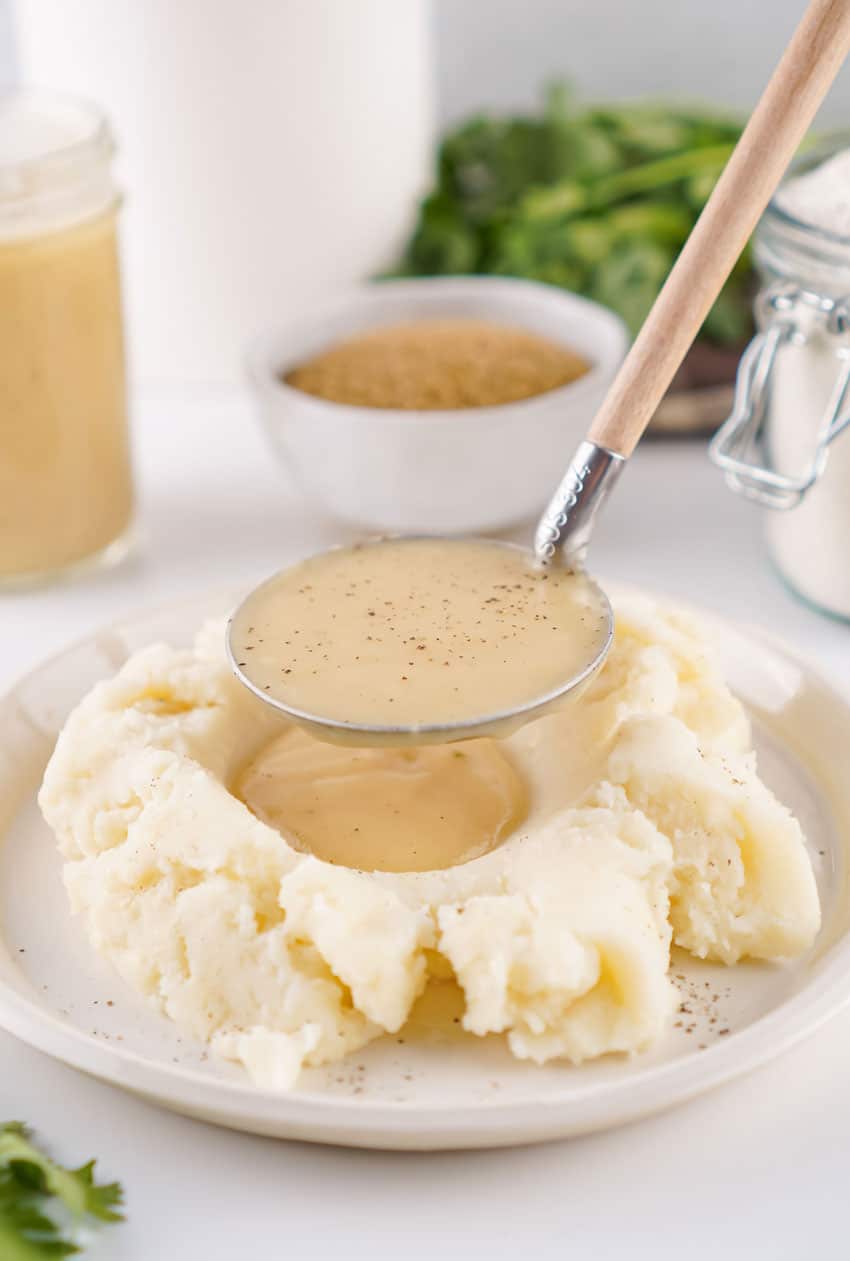 easy homemade brown gravy being ladled over mashed potatoes on a white plate