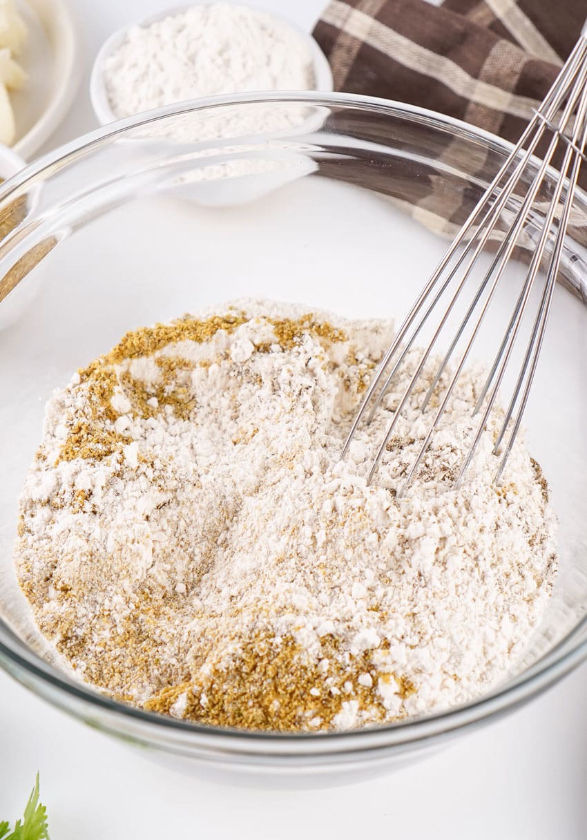 homemade brown gravy mix being whisked together in a large glass mixing bowl