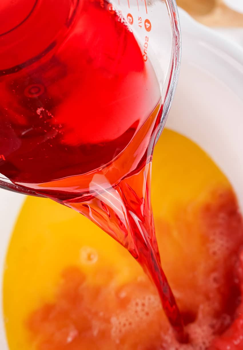 red juice being poured into a white slow cooker