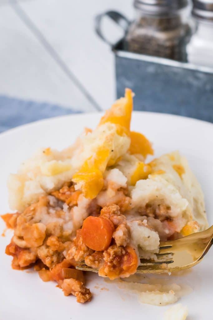 buffalo chicken shepherd's pie on a white dinner plate with a golden fork