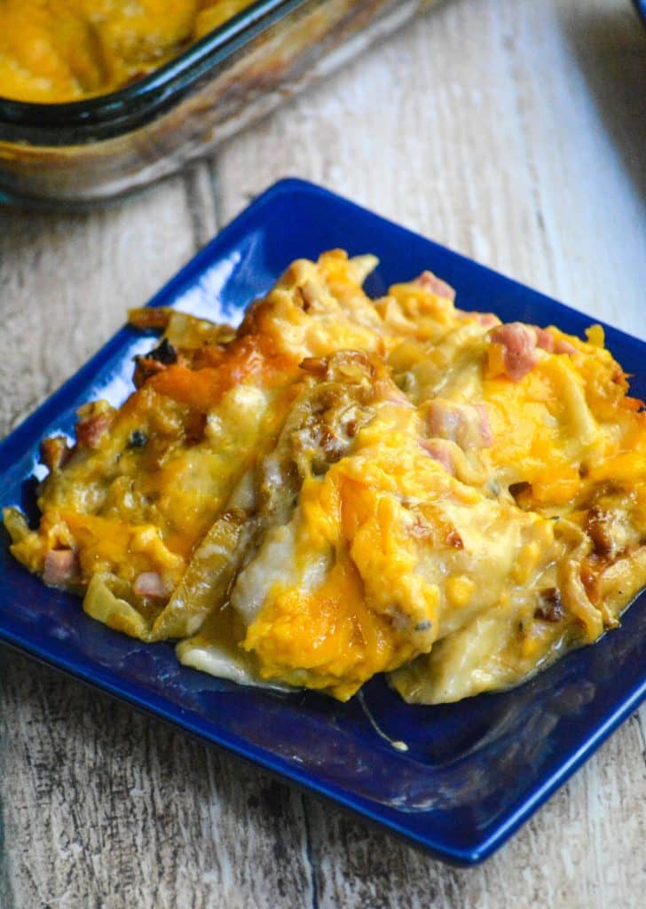 cheesy pierogi casserole with ham on a small, square blue plate 