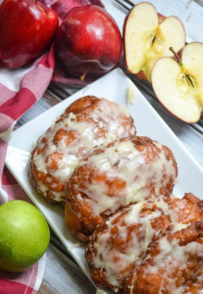 fried apple fritters lined up on a white platter
