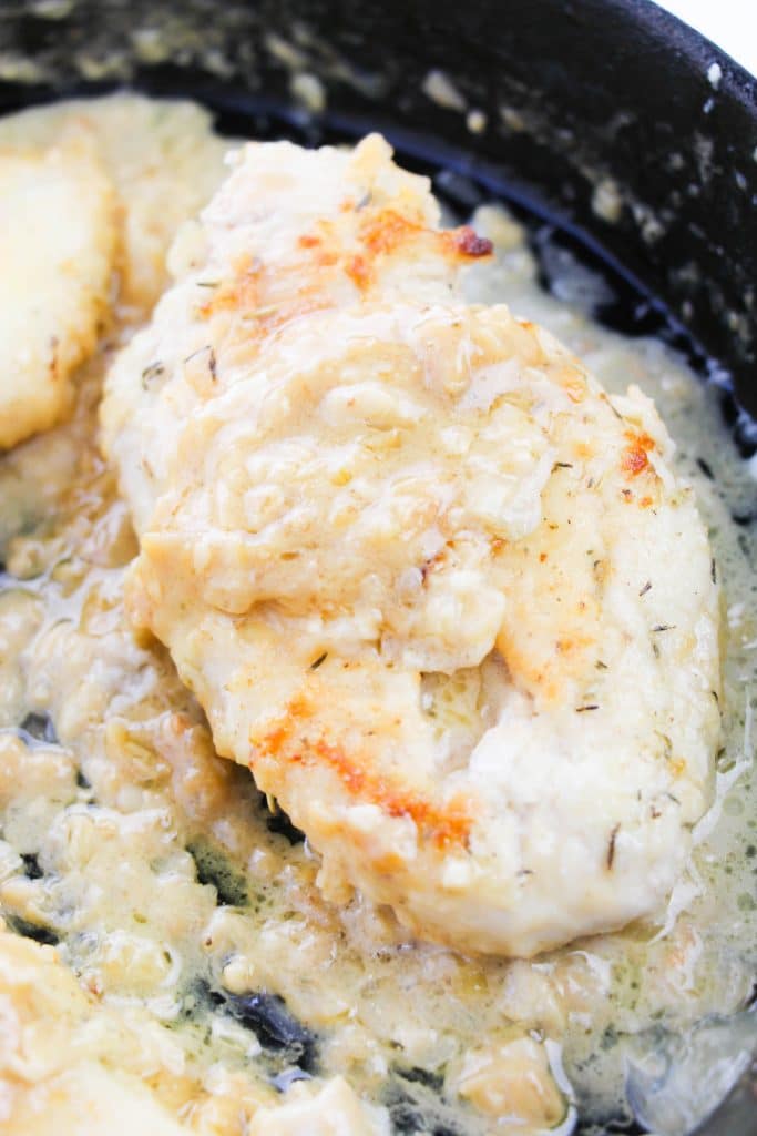 a smothered chicken breast covered in thick onion gravy in a cast iron skillet