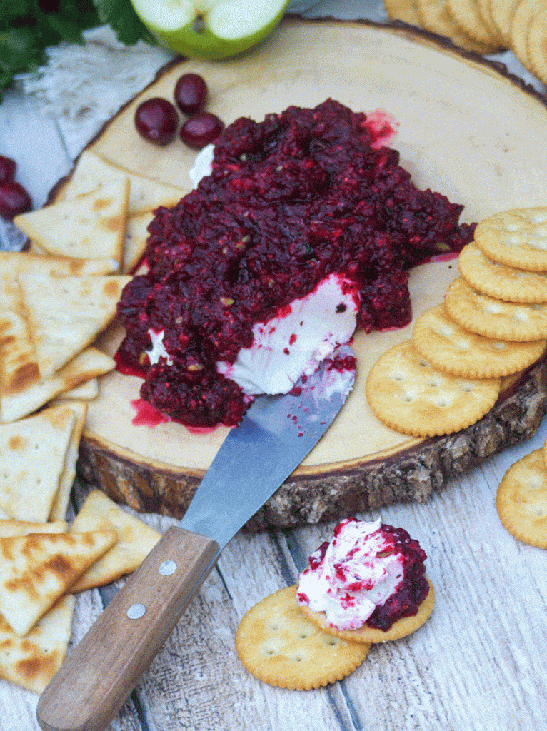 cranberry relish over a ball of cream cheese spread on a round buttery cracker