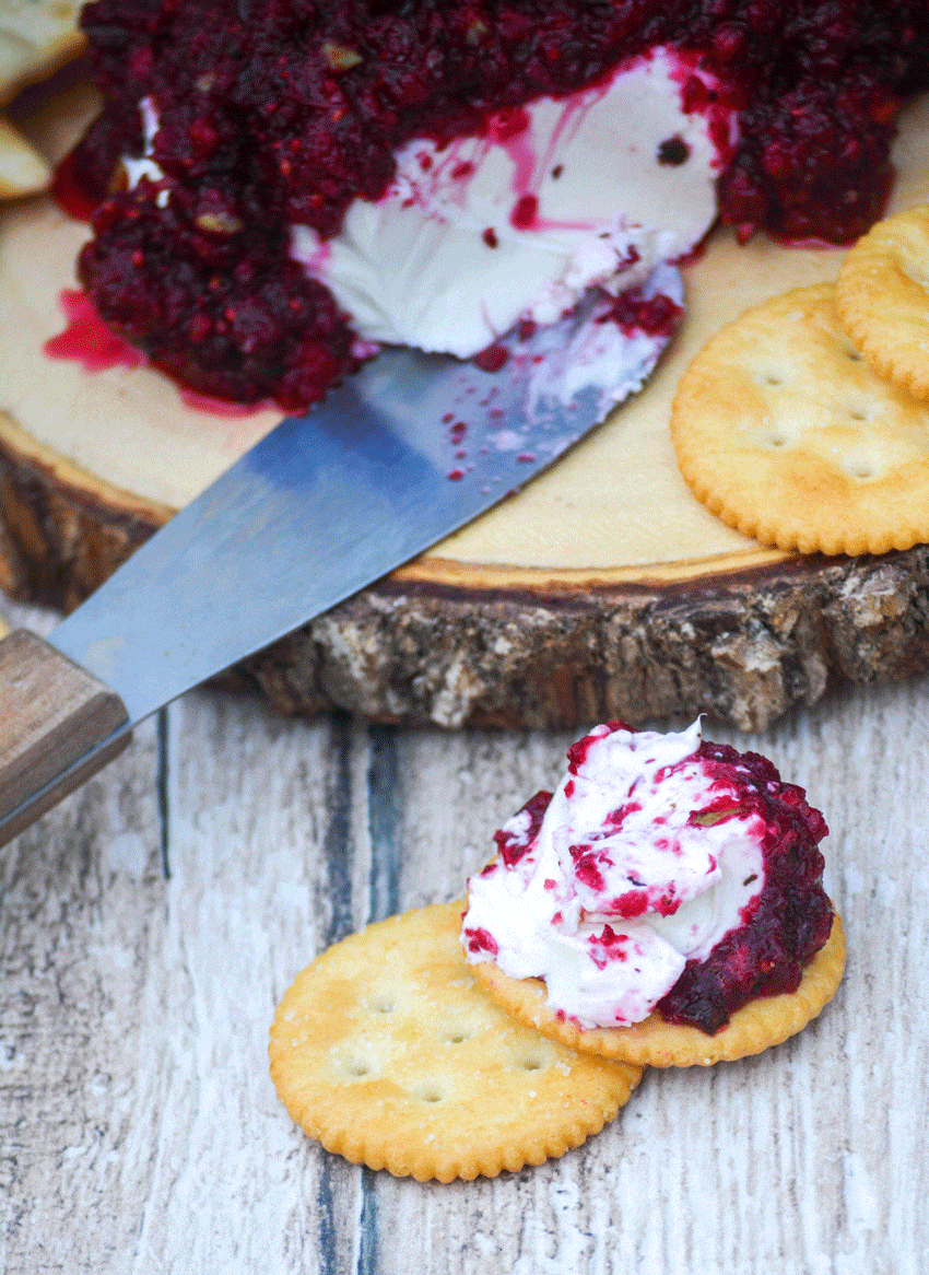 cranberry relish over a ball of cream cheese spread on a round buttery cracker