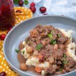 cranberry beef stew over mashed potatoes in large shallow gray bowls