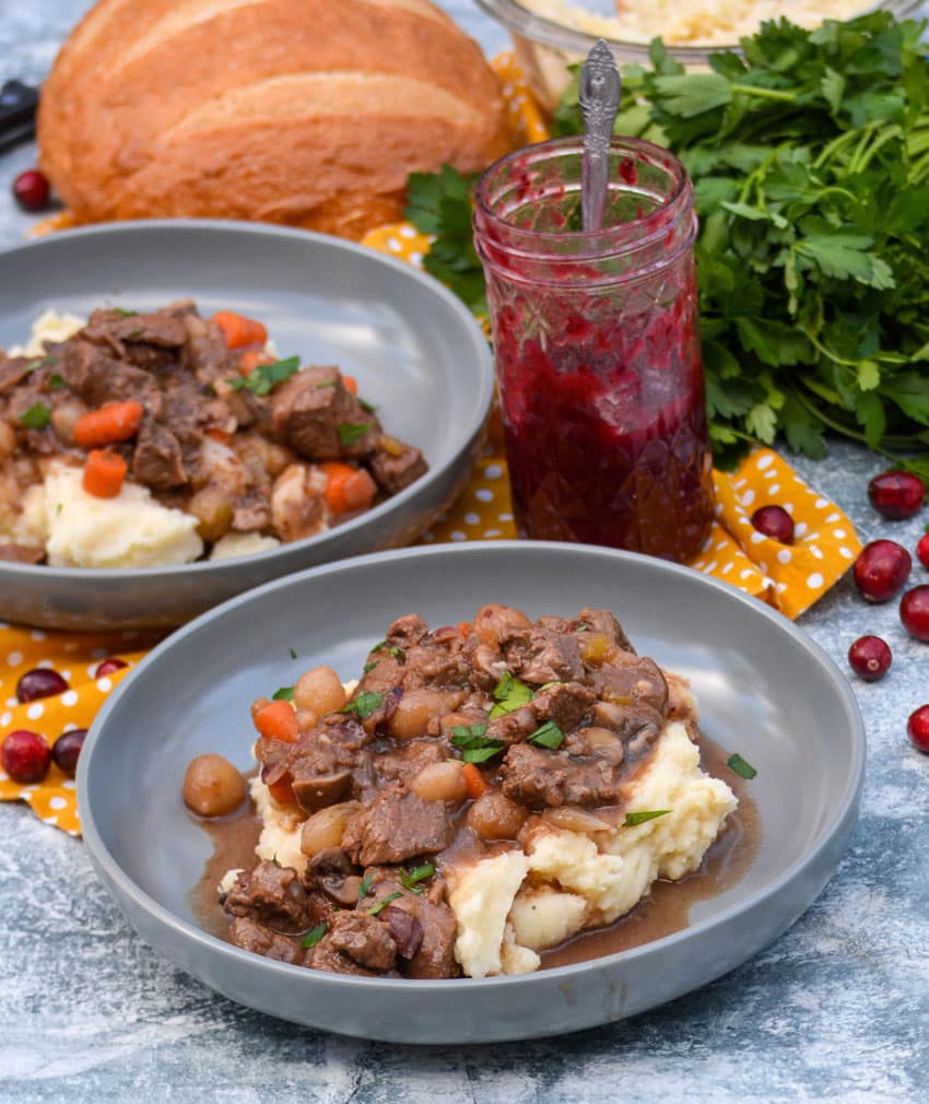 Cranberry Beef Stew cranberry beef stew over mashed potatoes in large shallow gray bowls